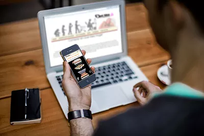 hombre visitando la sitio de Qué idea Hogar mediante la pc y un smartphone